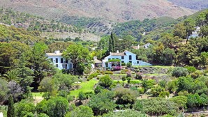 Una propiedad en la ladera con una casa grande rodeada de jardines exuberantes y árboles.