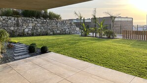 Un patio moderno al aire libre con un muro de piedra, césped y vistas a la ciudad.