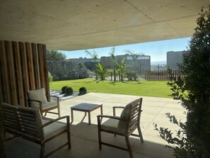 A patio with wooden furniture and a view of a grassy area with a stone wall and buildings in the background. - Casa da Arda: Villa with exclusive pool between sea and mountains, Afife (Viana do Castelo)
