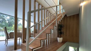 A modern staircase with wooden steps and metal railings, leading to a room with a view of greenery outside. - Casa da Arda: Villa with exclusive pool between sea and mountains, Afife (Viana do Castelo)