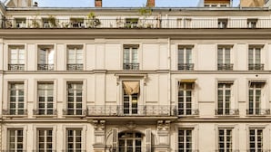 A multi-story building with a symmetrical facade, featuring evenly spaced windows, decorative iron railings on balconies, and a central entrance with an archway. - Merveil - Luxury Suite -ChampsElysees- Florentin I (Paris)