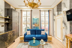 Un salon luxueux avec un canapé bleu, une table basse en verre et un grand tableau abstrait.