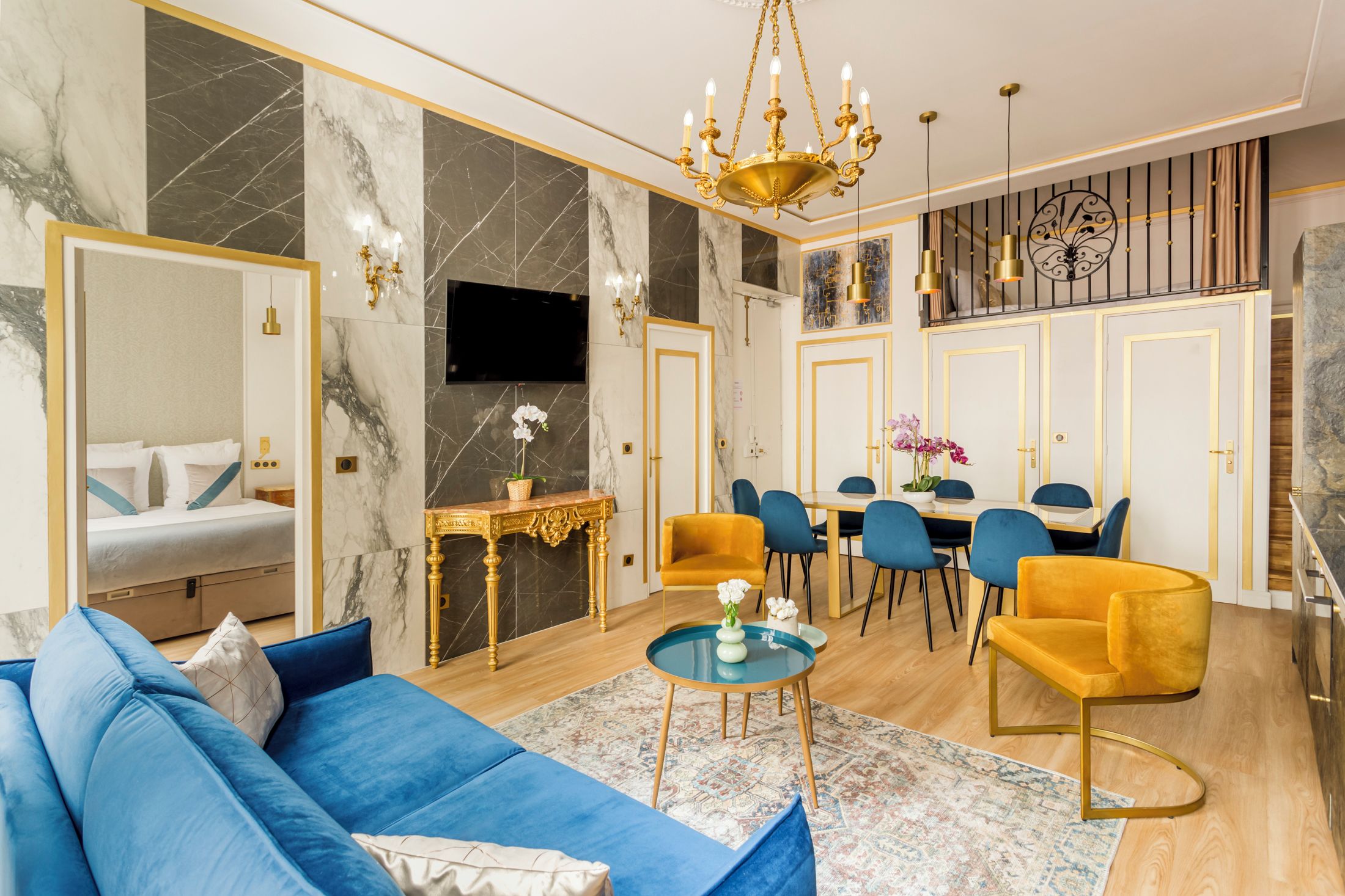 A modern living room with a blue sofa, a gold-framed console table, and a chandelier.
