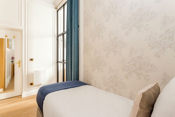 Un dormitorio con cama, una puerta que da al baño y una ventana con cortinas.