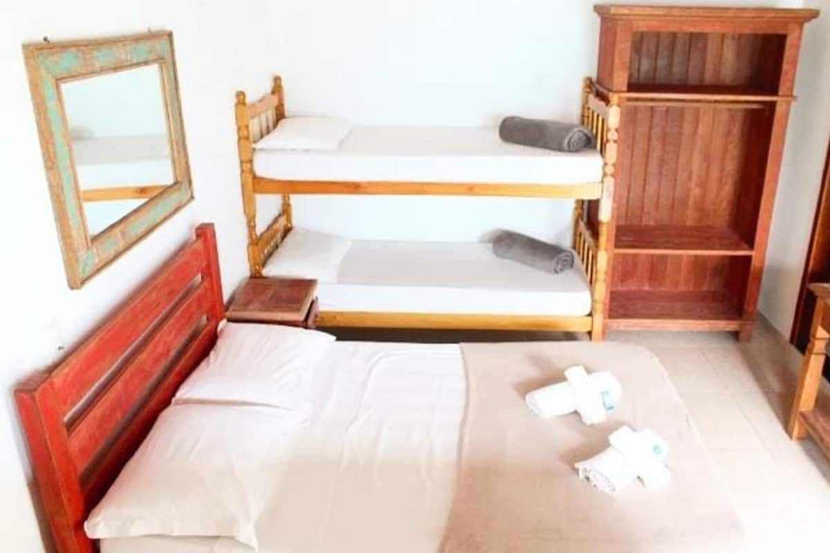 A bunk bed room with a wooden headboard, a small bedside table, a mirror, and a wooden cabinet.
