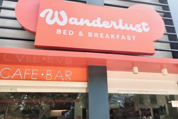 Letrero de Wanderlust Bed & Breakfast con un café-bar en la parte inferior.