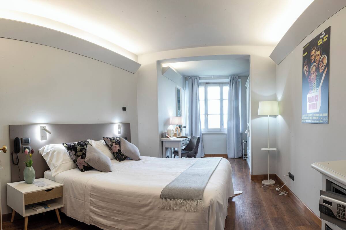 Ein modernes Hotelzimmer mit einem großen Bett, einem Nachttisch, einer Lampe und einem Schreibtisch mit Stuhl.