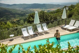 Una piscina al aire libre de temporada, sombrillas