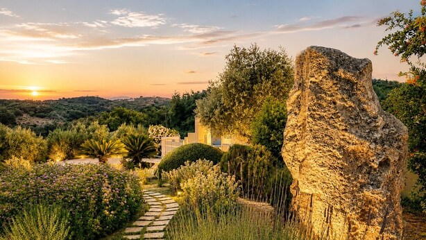 A garden pathway leading to a building with a large rock sculpture. - Deluxe Villa Ianthos - Outdoor Hot Tub & Kids Pool (Rethymno)