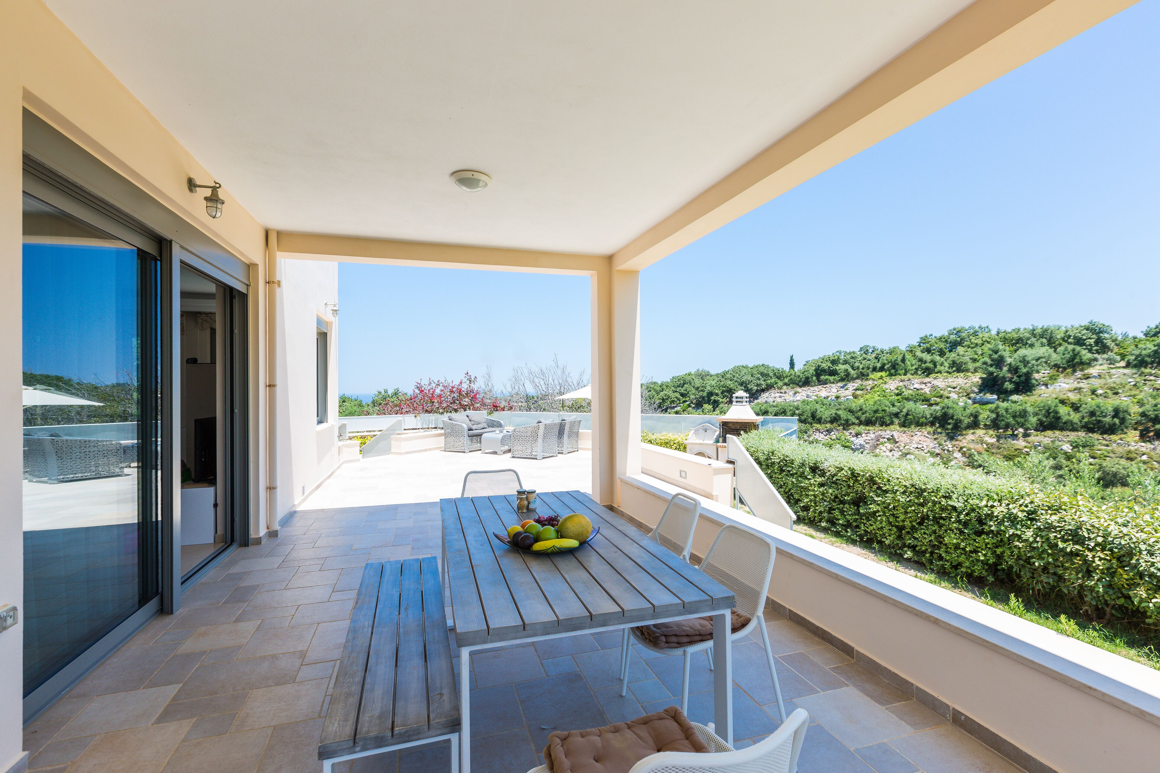 Ein Balkon mit Holztisch, Stühlen und einer Obstschale.