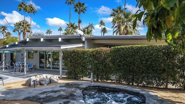A modern house with a swimming pool, patio furniture, and palm trees. - Alexander in the Sun - Mid‑Century Pet‑Friendly Oasis: Pool, Spa & Mountains (Palm Springs)
