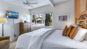 A bedroom with a bed, a TV, a desk, a chair, a window with a view, and a ceiling fan. - Alexander in the Sun - Mid‑Century Pet‑Friendly Oasis: Pool, Spa & Mountains (Palm Springs)