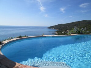 A clear blue pool with a curved edge, surrounded by a stone deck and a view of the sea and hills. - Stunning 2/4-person apartment in a villa with a pool and panoramic ocean views (Conca)
