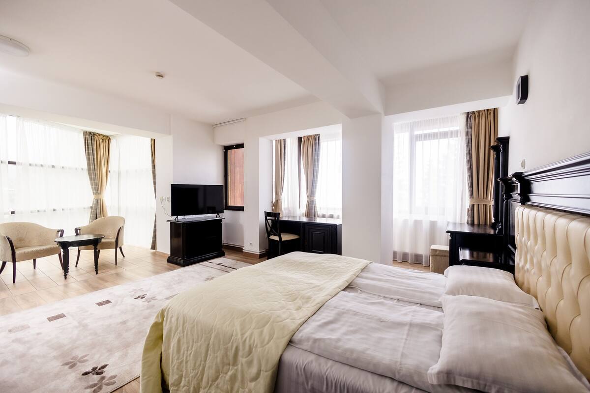 Une chambre d’hôtel avec un grand lit, un bureau, une télévision et deux chaises.