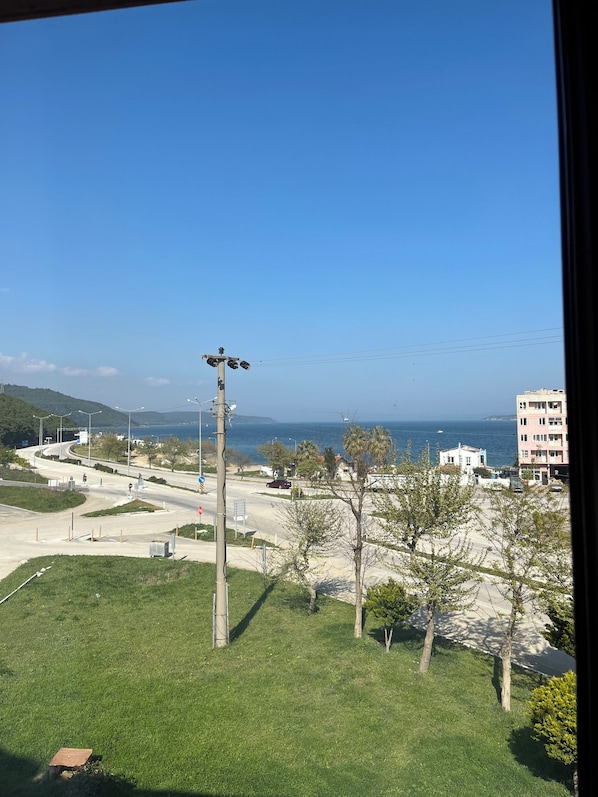 A view of a coastal road with a clear sky, a streetlight, and a building in the distance. - Doyuranlar Ata Hotel (Eceabat)