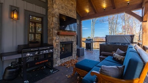 Un espace de vie extérieur accueillant, doté d’une cheminée en pierre, d’un barbecue et d’un coin salon confortable.