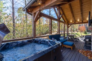 A hot tub area with wooden deck and seating, surrounded by trees.
