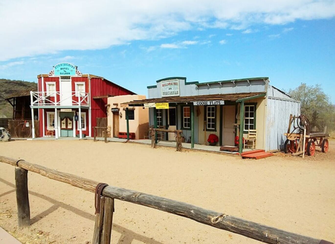 A Western-style hotel with a red facade, a sign for 'Coose Flats', and a wooden fence in the foreground.
