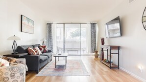 A modern living room with a sofa, a coffee table, and a TV mounted on the wall.