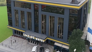 Ein modernes Hotel mit flachem Dach, großen Fenstern und einem Schild mit der Aufschrift 'EMPIRE HOTEL'.