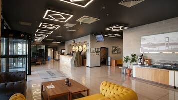 A modern lobby with a reception desk, seating area, and a large digital screen displaying a cityscape.