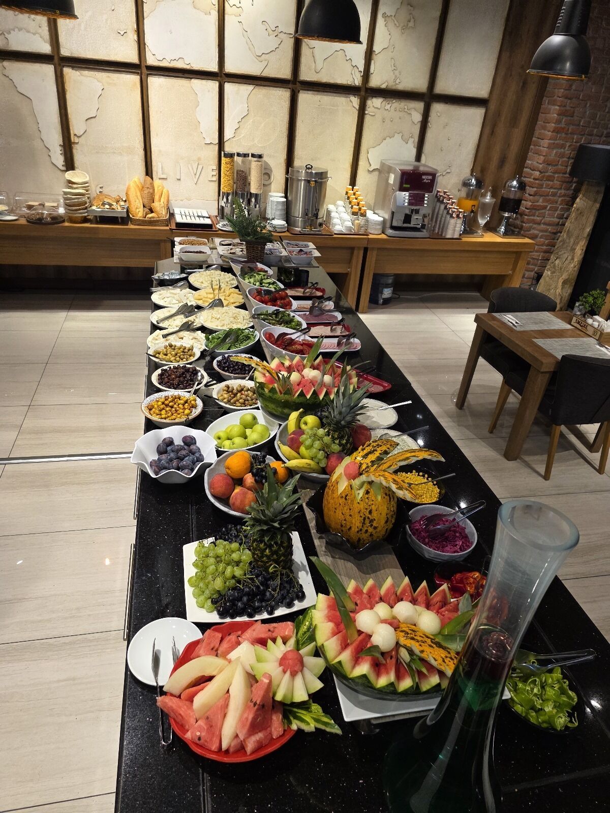 A buffet table with a variety of fruits and vegetables, including watermelon, grapes, and pineapple.
