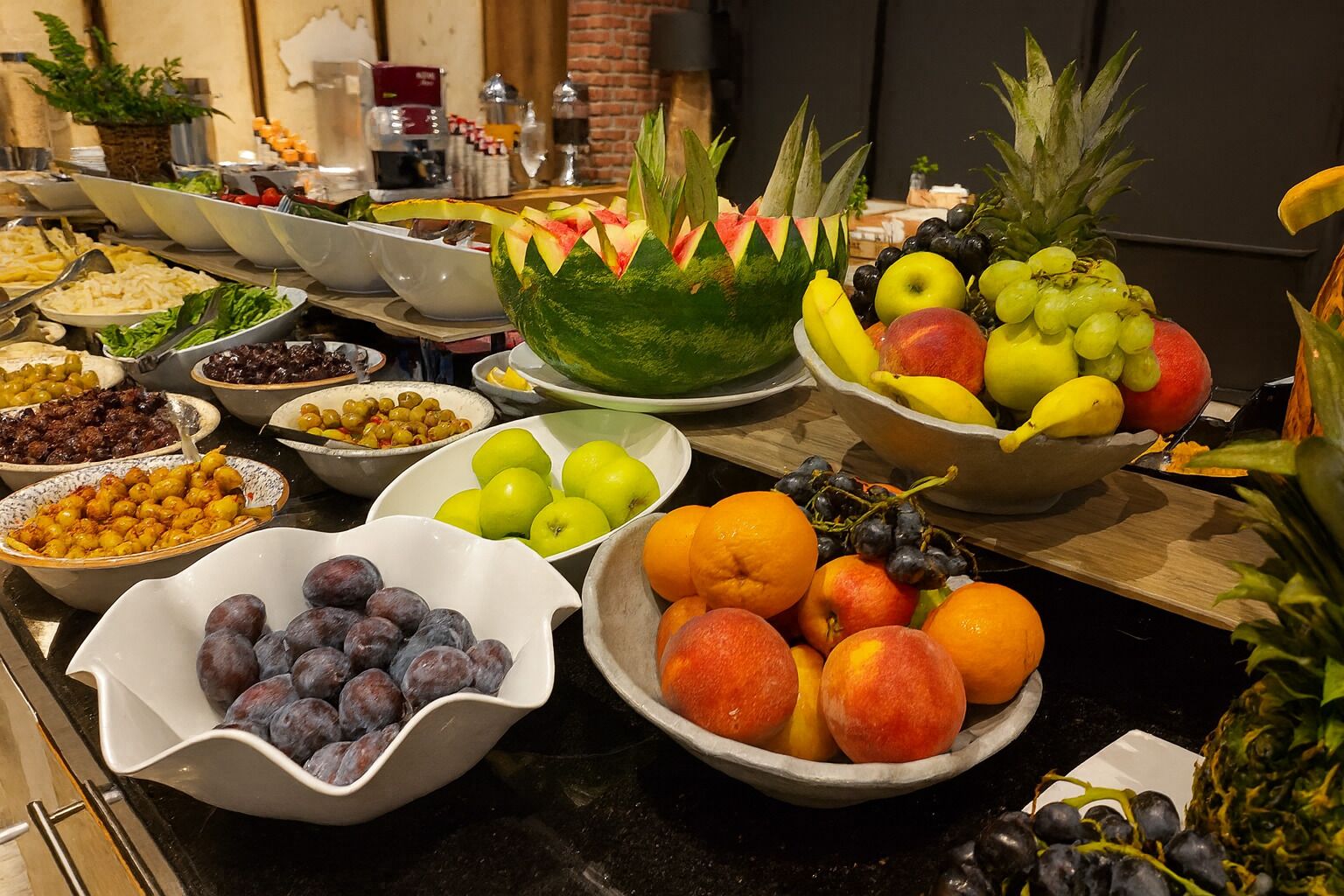 Ein reichhaltiges Buffet mit verschiedenen Früchten und Gemüsesorten, darunter Äpfel, Orangen, Trauben und einer Wassermelone als Mittelpunkt.