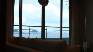 A room with a large window overlooking a body of water and a distant island.