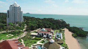 A resort with a large building, a beach, and a pool area.