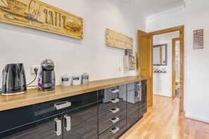 Een moderne keuken met een houten aanrecht, zwarte kastjes en een koffieapparaat.