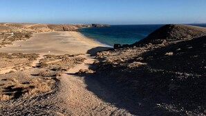 A coastal landscape with a beach, rocky terrain, and a clear sky. - Villa Maria Luisa near the beach with private pool and Wi-Fi (Playa Blanca)