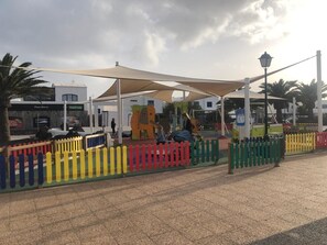 A playground with play structures, a colorful fence, and a covered seating area.