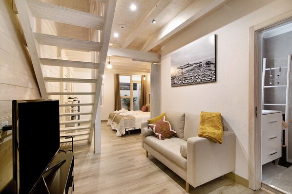 Un intérieur moderne avec un canapé, un téléviseur, un escalier en bois et un lit offrant une vue agréable.