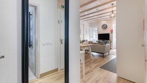 A modern interior with a wooden floor, a sofa, a dining table, and a television.