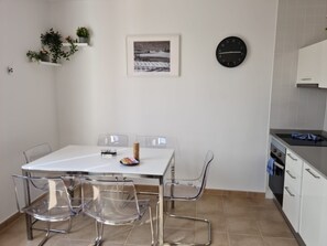 Una cocina moderna con armarios blancos, un reloj negro y un cuadro en la pared.
