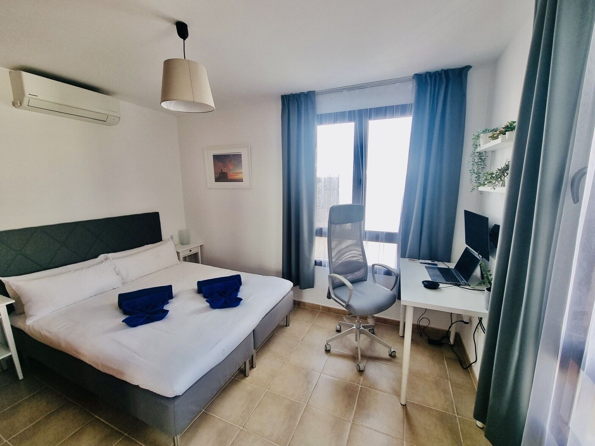 Una camera d'albergo con un letto, una scrivania, una sedia e una finestra con tende.