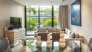 A modern living room with a large TV, a glass coffee table, and a sofa. - Oceana Home Travel Mexico  (Playa del Carmen)