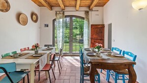 Un espace repas doté d’un plafond en bois, d’une grande fenêtre donnant sur un paysage verdoyant et d’une porte.