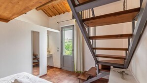 Une chambre avec un lit, un escalier en bois et une vue sur l’extérieur.