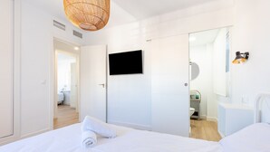 A modern hotel room with a bed, a television, a bathroom, and a mirror.