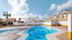 Ein Pool mit Stufen, umgeben von einem weißen Gebäude mit gelben Akzenten und einem Balkon.