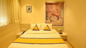 A hotel room with a bed, a nightstand, a telephone, and a picture on the wall. - The Dorm Inn (Nashik)