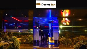 A hotel entrance with a neon sign for a restaurant and a glass door. - The Dorm Inn (Nashik)