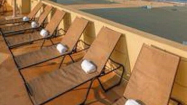 Un balcon d’hôtel donnant sur la plage, avec des chaises longues et une vue sur l’océan.