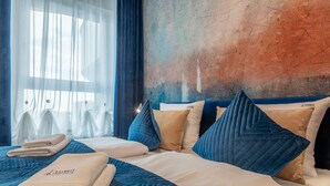 Ett hotellrum med en stor säng, blå sängkläder och en vägg med en intressant yta.
