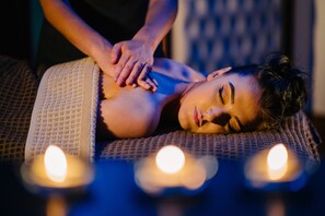 A person receiving a massage with candles in the foreground. - Burrendale Hotel Country Club & Spa (Newcastle)