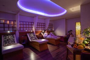 A spa room with two massage chairs, a small table with fruit, and a decorative wall panel. - Burrendale Hotel Country Club & Spa (Newcastle)