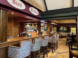 A bar area with a long counter, bar stools, and a variety of bottles and glasses. - Burrendale Hotel Country Club & Spa (Newcastle)