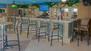 A bar area with multiple stools and a television screen. - Bch Q 1BR 1BA w Ocean Front Balcony - sleeps 6 (Virginia Beach)