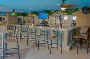 A bar area with multiple stools and a television screen.